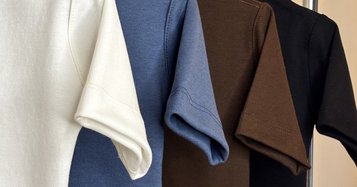 Blusas infantis Banim em marfim, índigo, marrom e preto penduradas lado a lado